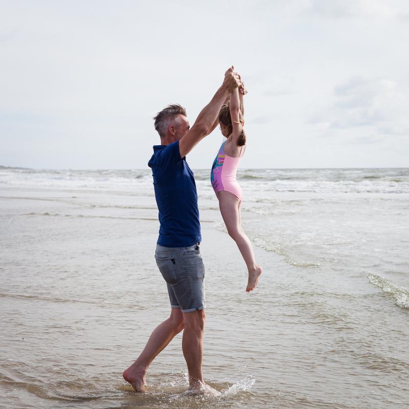 Man with child playing by the sea